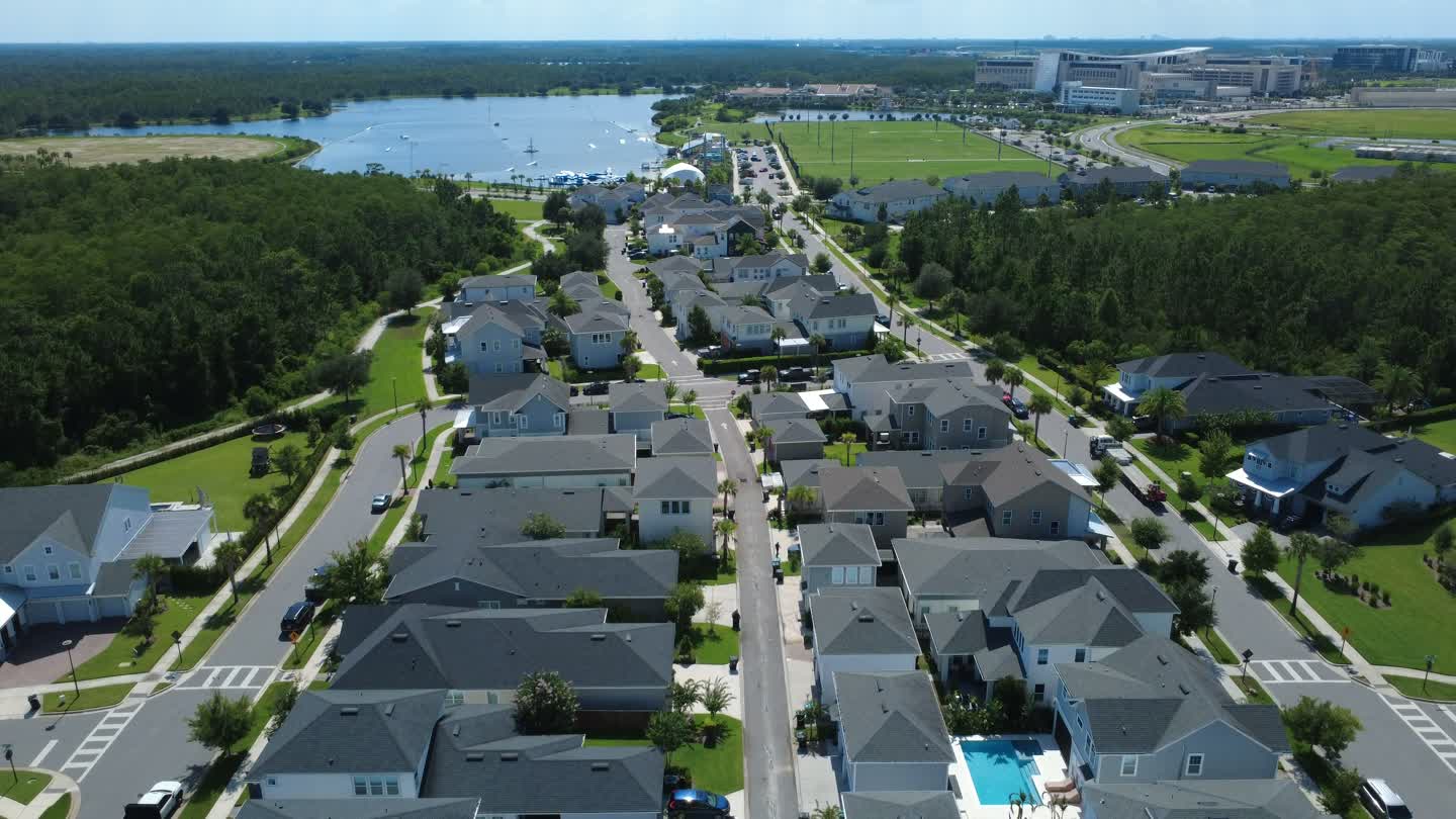 Aerial view of a waterfront neighborhood with homes, green spaces, and a community marina